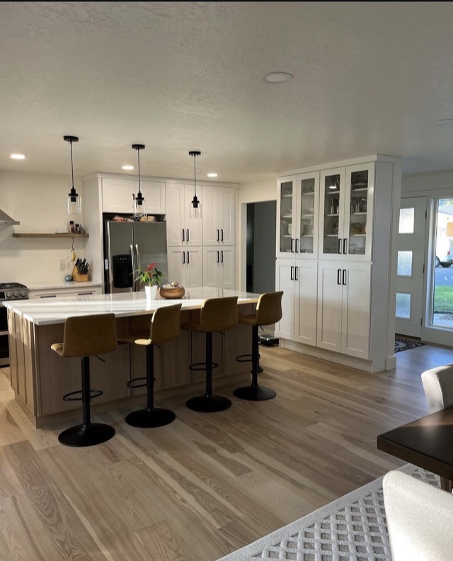 Open concept kitchen with island seating and glass-door pantry cabinet