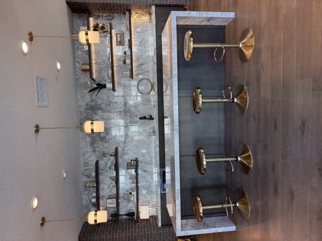 Marble waterfall bar with floating shelves and gold pendant lighting