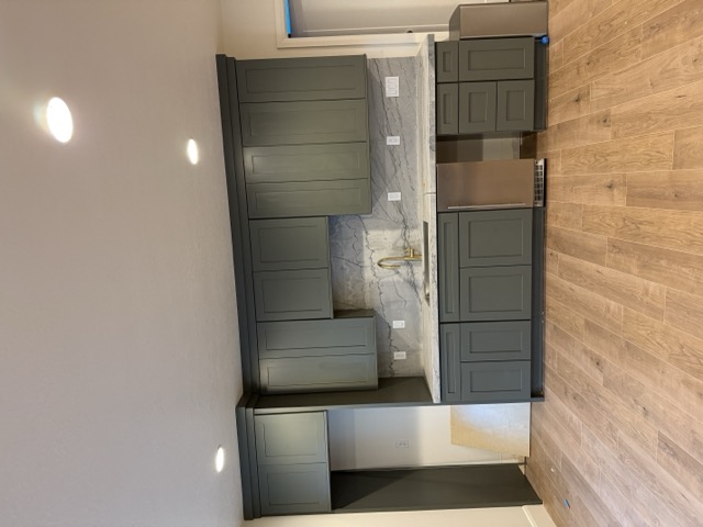 Sage green shaker cabinets with marble backsplash and built-in wine cooler