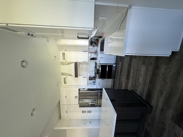White shaker kitchen with dark island and custom range hood