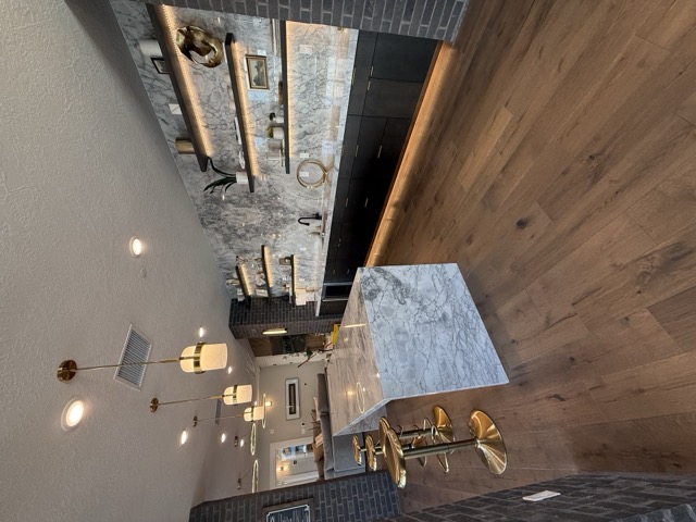 Marble bar and kitchen with floating shelves and brick accent wall