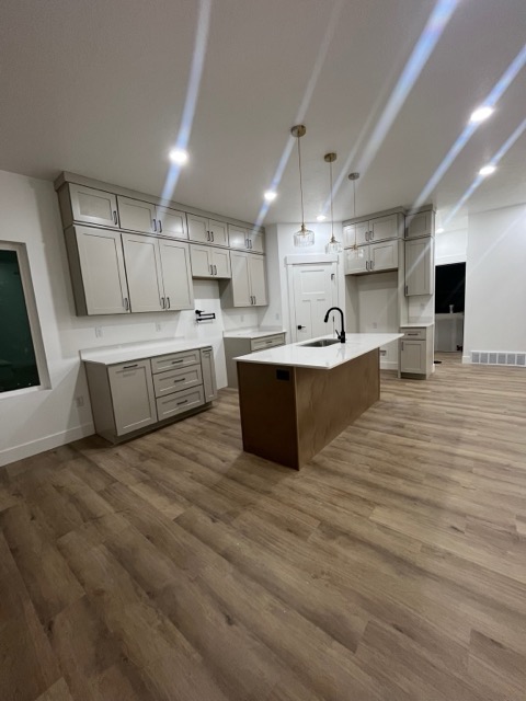 Greige shaker cabinets with matte black pulls, white quartz counters and a natural stained wood island with fluted glass pendants