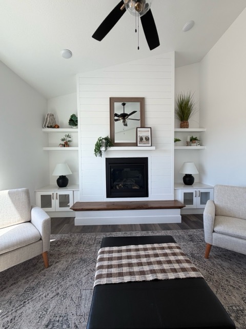 White shiplap fireplace with a stained wood mantel flanked by built-in cabinets with glass-front upper doors