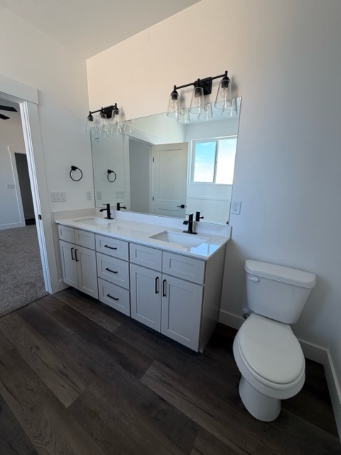 Bright white shaker double vanity with quartz countertop and matte black hardware over dark plank flooring