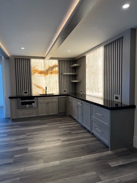 Wet bar elevation showing fluted slat walls, floating corner shelves and a stainless microwave drawer under black quartz