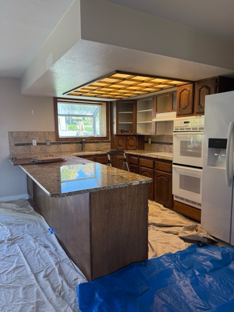 The original U-shaped oak kitchen before remodel with tumbled tile backsplash and white double wall ovens