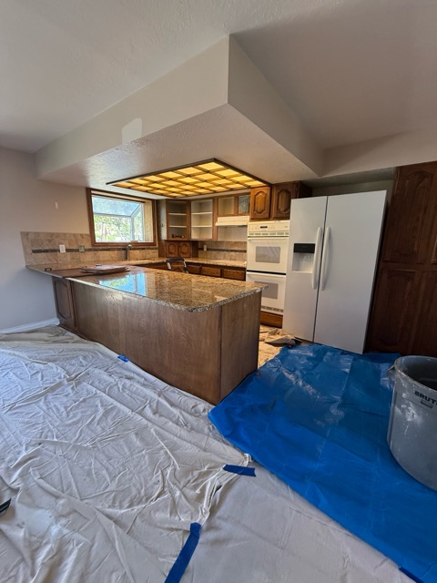 The original kitchen before remodel with dark oak cathedral-arch cabinets, gold granite and a fluorescent ceiling light box