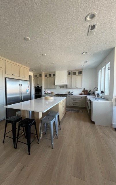 Open two-tone kitchen with cream floor-to-ceiling pantry cabinets and greige perimeter cabinetry