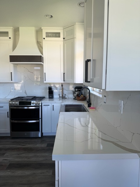 Calacatta quartz peninsula and matching slab backsplash with white shaker cabinets and a stainless undermount sink
