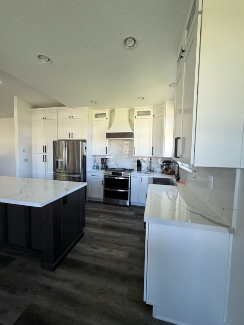White shaker kitchen with a dark espresso island, Calacatta quartz peninsula and matching slab backsplash on charcoal floors