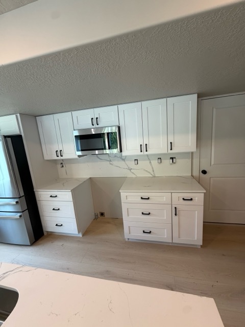 Floor-to-ceiling white shaker pantry and built-in wall oven cabinet against a full-height white quartz backsplash